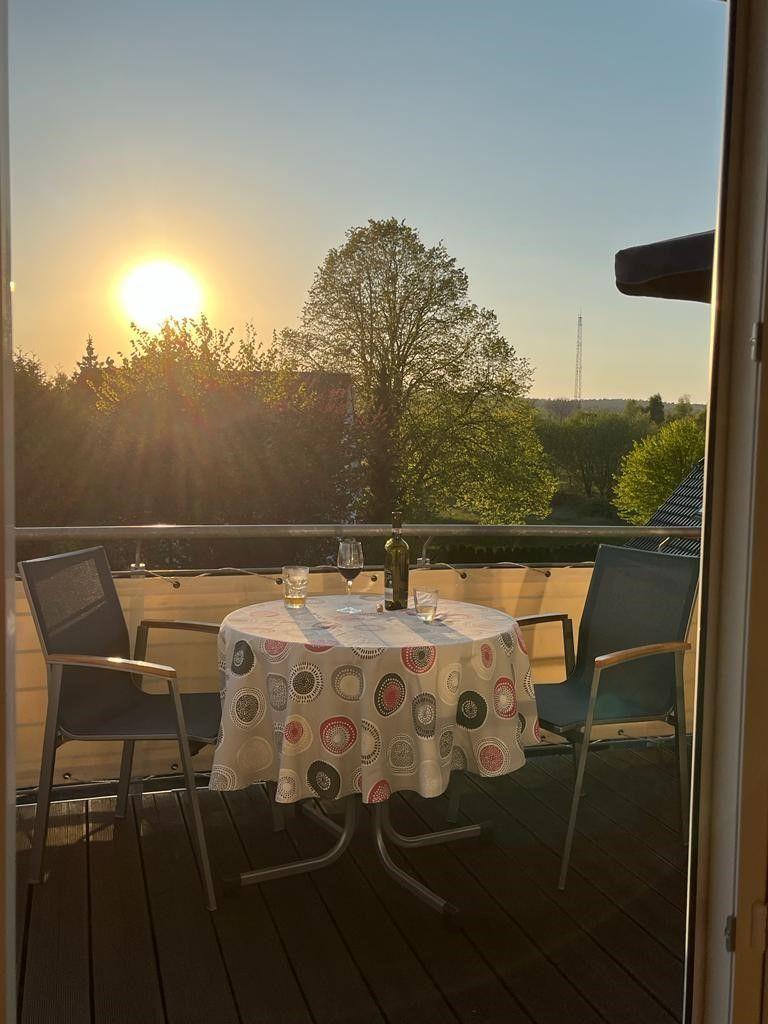 Terrasse mit Tisch, Stühlen und Sonnenuntergang. Tischdecke mit runden Mustern.