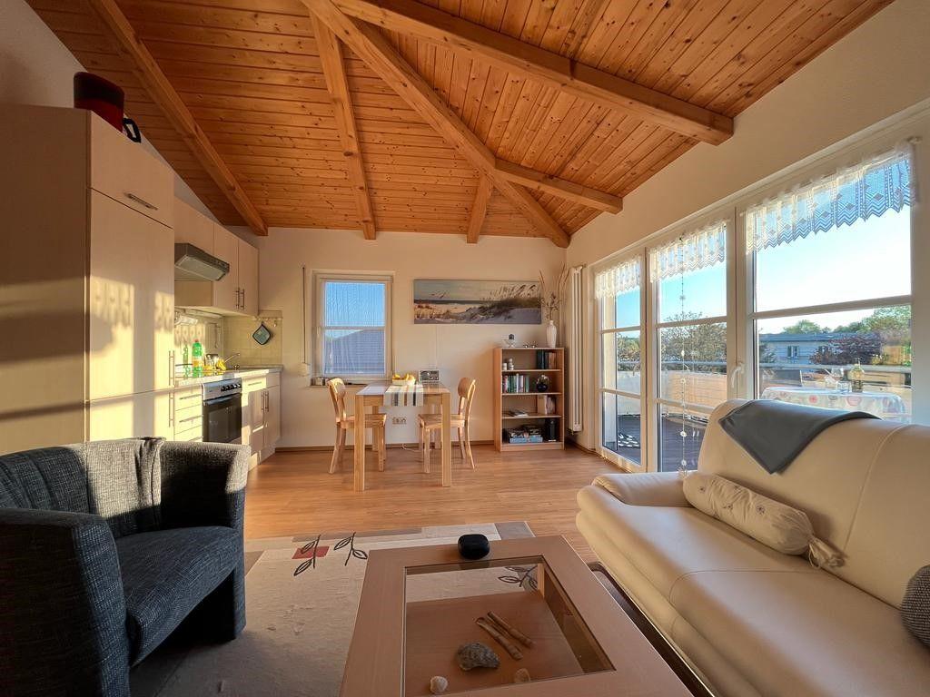 Wohnraum mit Essbereich, Küche und großem Fenster. Holzdecke und Holzboden.