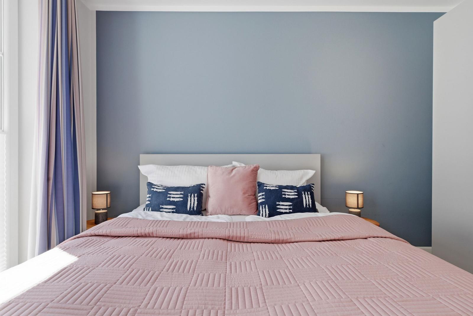 Schlafzimmer mit Bett, Kissen und blauer Wand