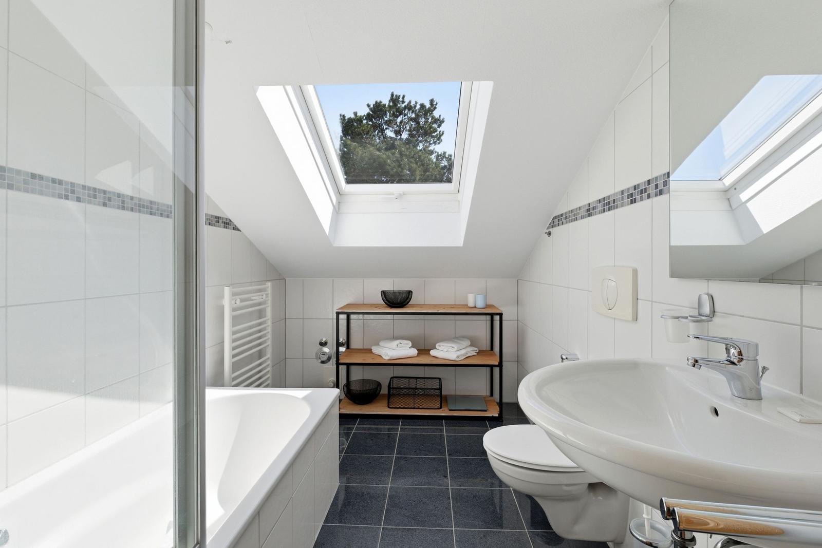 Badezimmer mit Dusche, Badewanne, Toilette und Waschbecken unter Dach