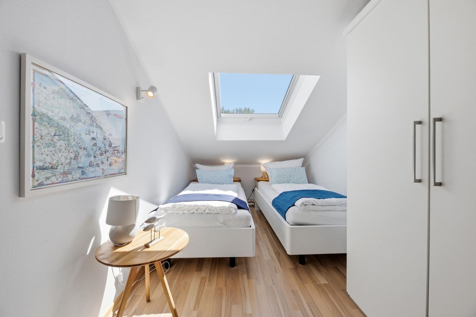 Zwei Einzelbetten unter Dachschrägen mit Dachfenster und Kleiderschrank.
