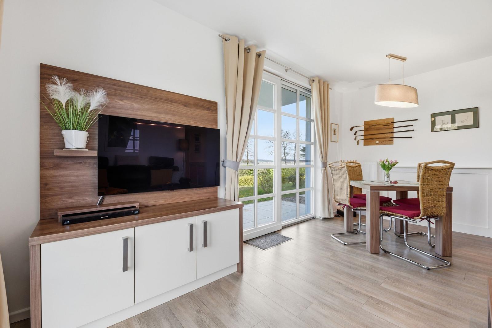 Wohn- und Essbereich mit TV, Esstisch und Blick auf den Garten.