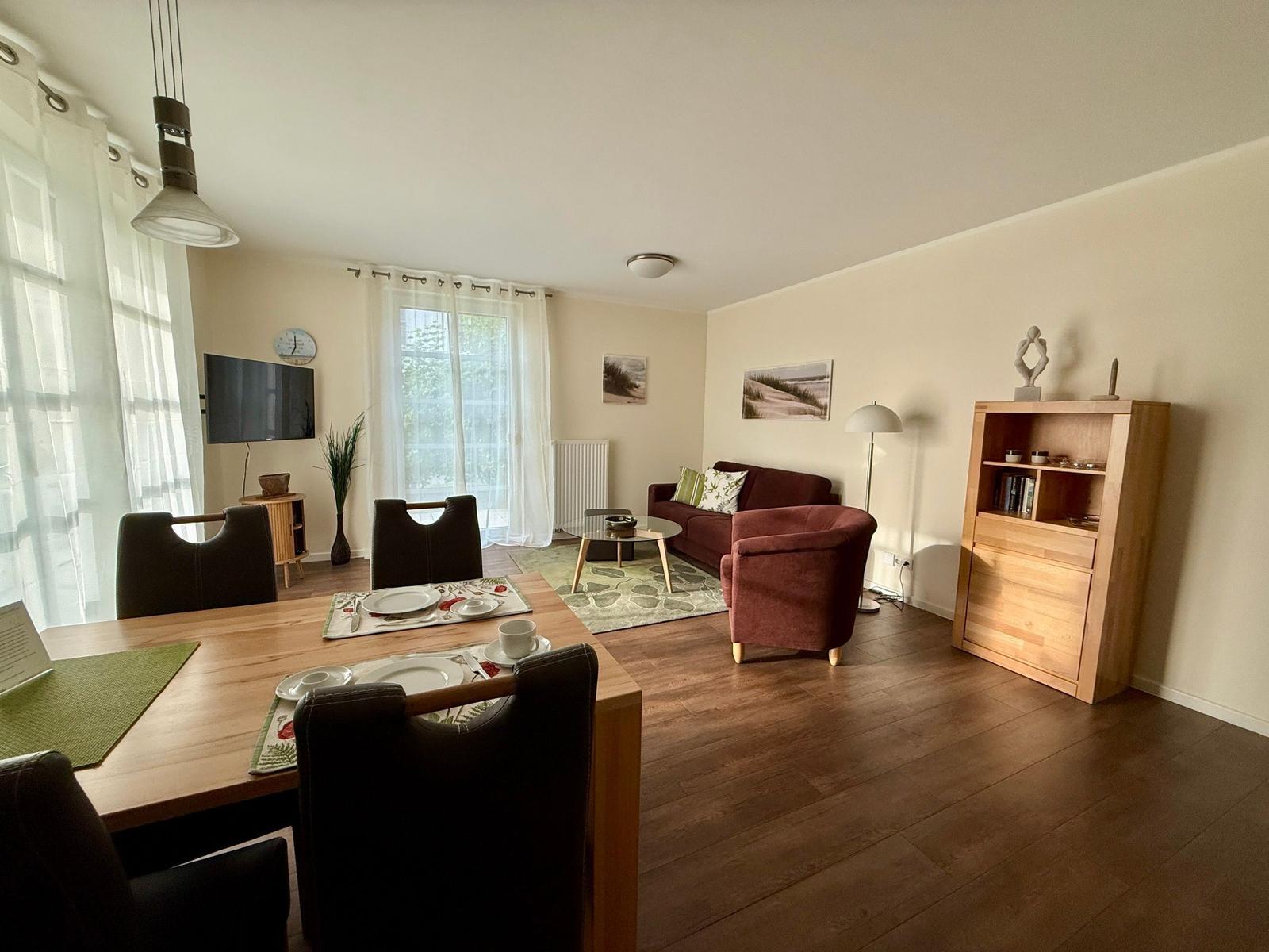 Wohn- und Essbereich mit Holzboden, Sofa, Esstisch und TV.
