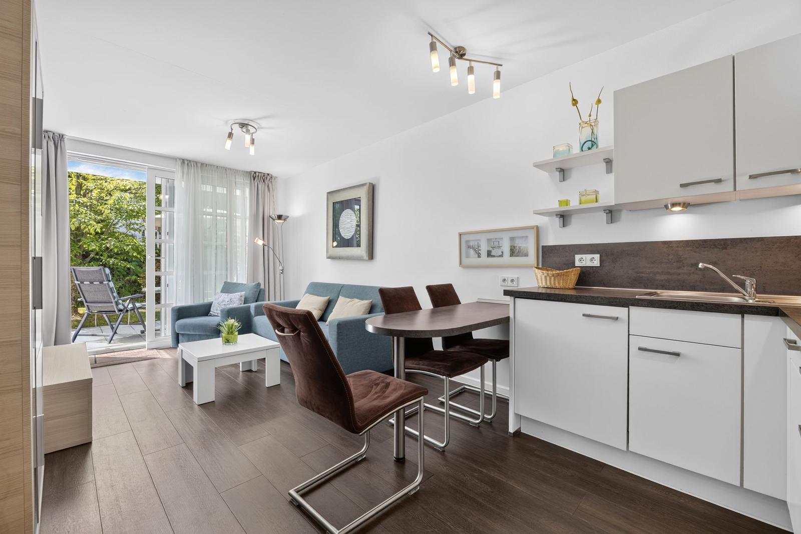 Wohnküche mit Essbereich, Sofa und Terrasse mit Gartenblick.
