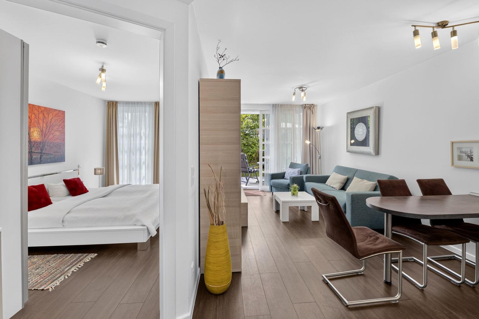 Wohnung mit Schlafzimmer, Wohnbereich und Essbereich. Holzboden und moderne Einrichtung.