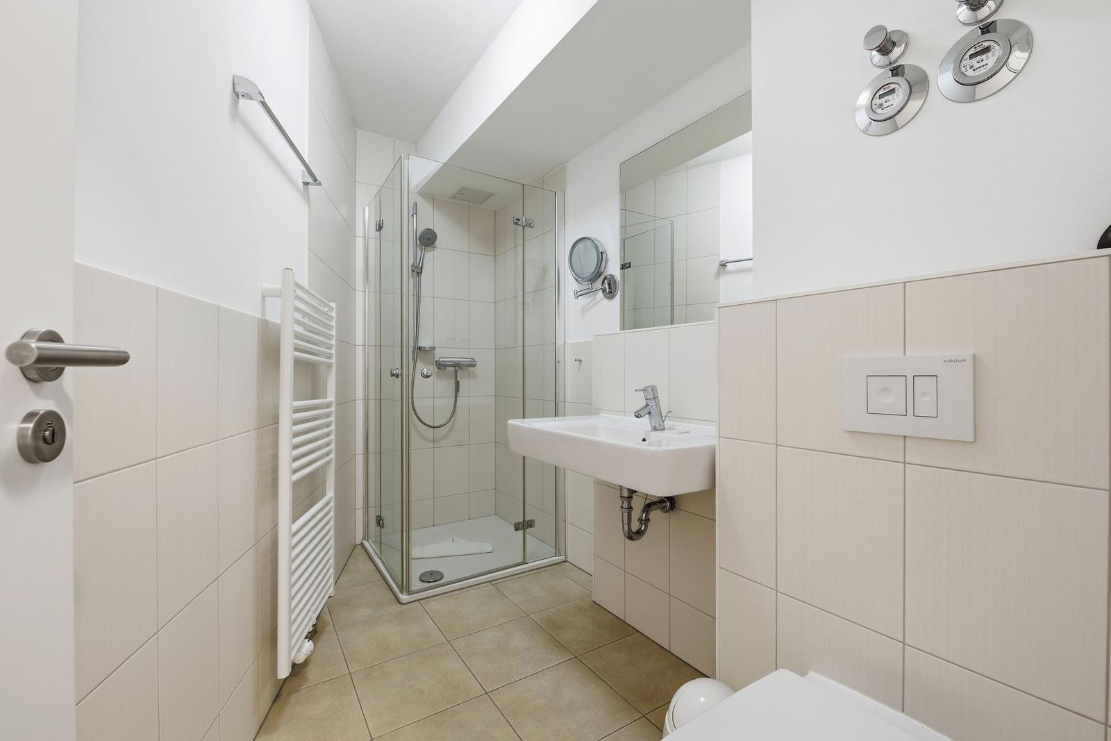 Badezimmer mit Dusche, Waschbecken und Heizkörper