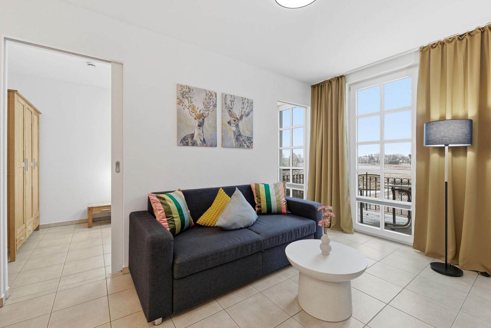 Wohnzimmer mit Sofa, Tisch und Fenster zur Terrasse