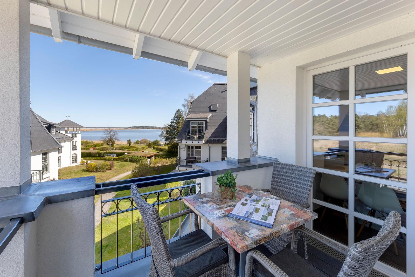 Terrasse mit Tisch und Stühlen. Blick auf Garten und Wasser.