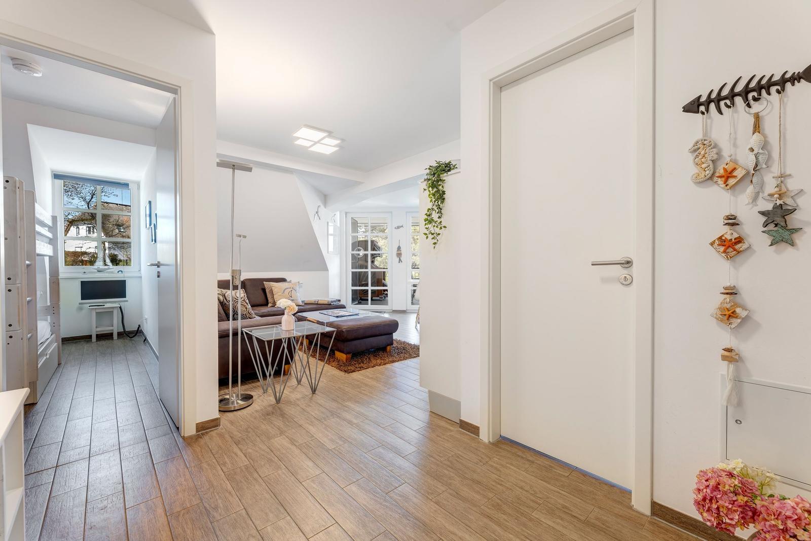 Wohnung mit Wohnzimmer, Schlafzimmer und Flur. Holzdielen, Sofa, TV und Dekoration.