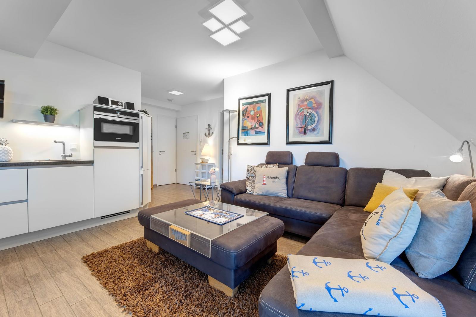 Wohnküche mit Sofa, Couchtisch und Küchenzeile unter Dachschrägen.