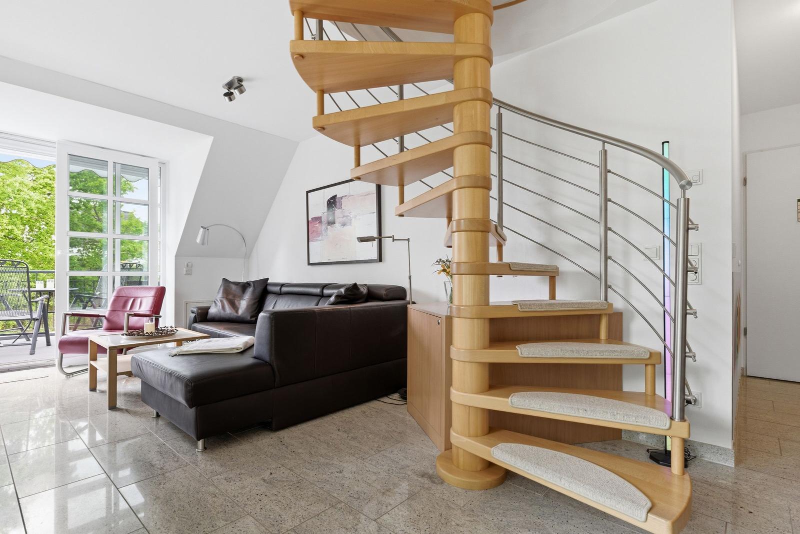 Living room with spiral staircase, leather sofa, and balcony view.