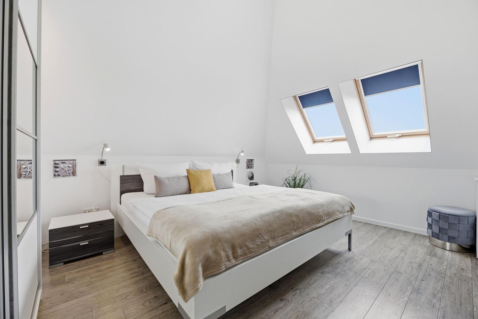 Bedroom with double bed, two skylights, and wooden floor.