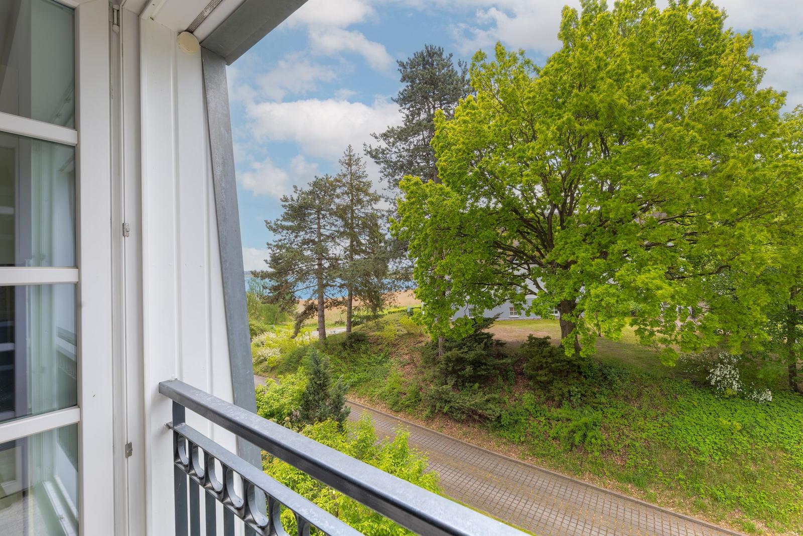 Balcony with view of green trees and a paved path.