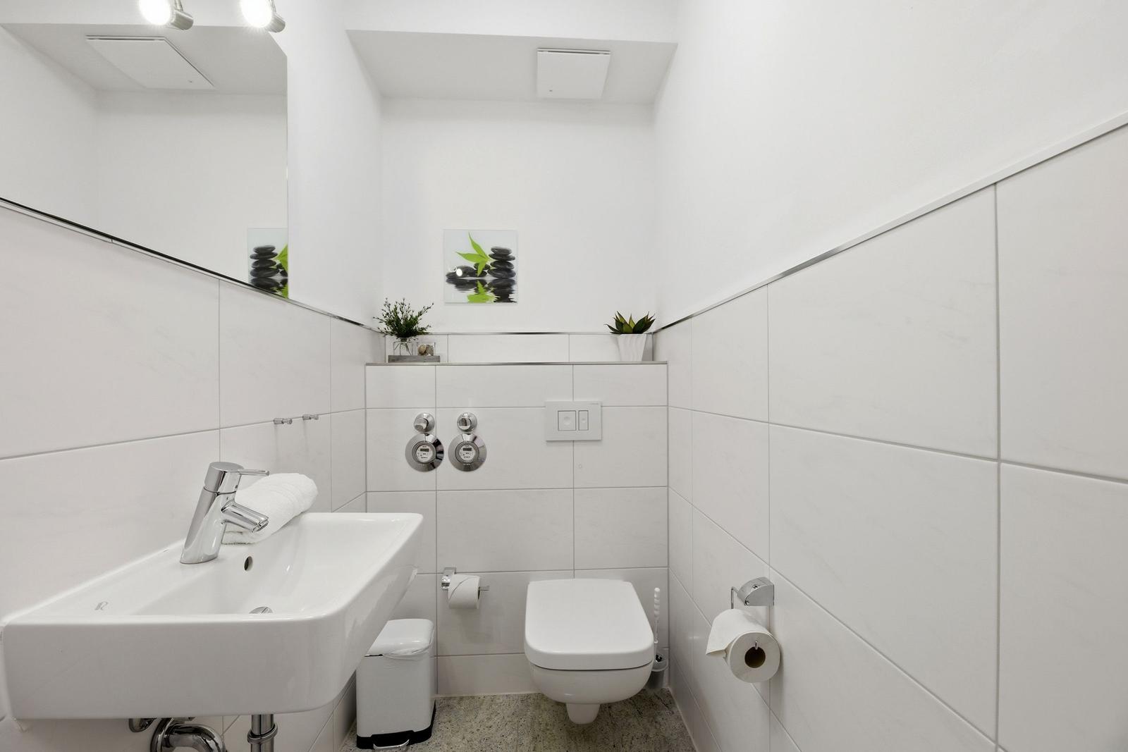 Bathroom with sink, toilet, and mirror on the wall.