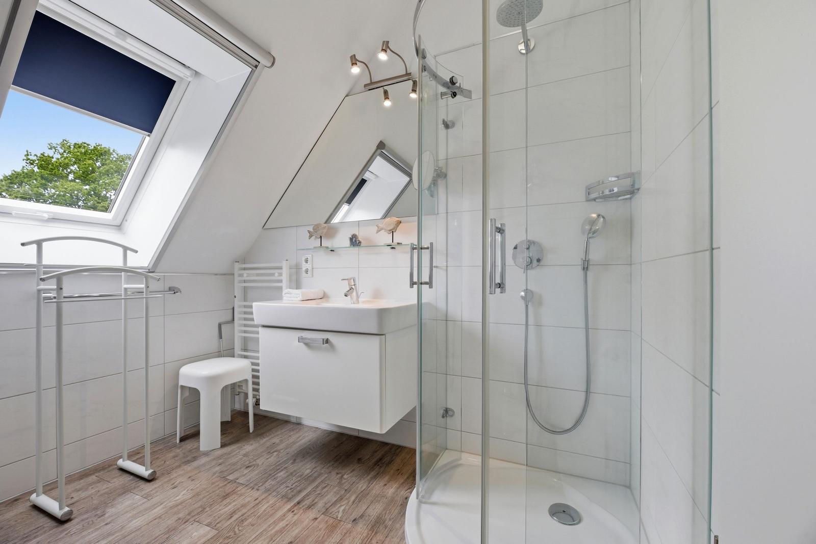 Bathroom with shower, sink, and skylight overlooking trees.