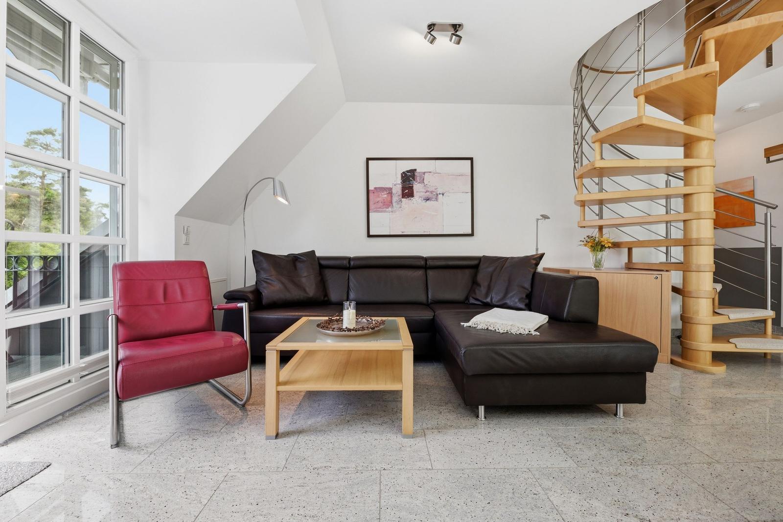 Living room with brown sofa, red chair, and wooden staircase.