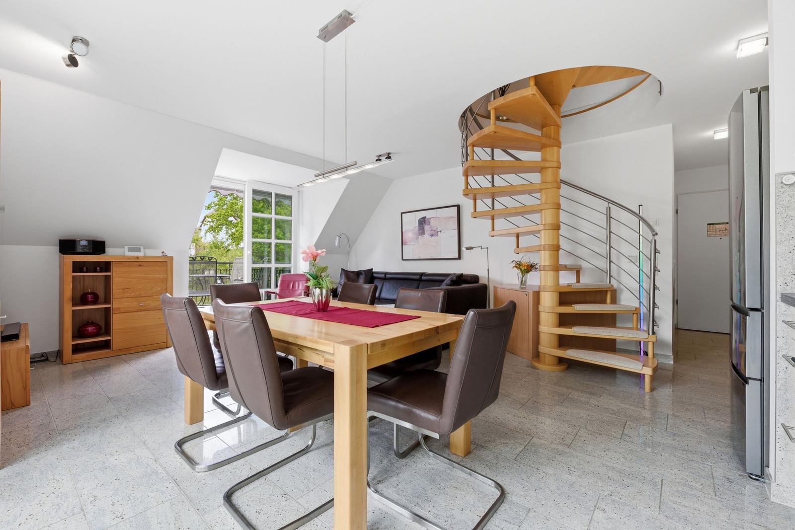 Dining area with table, chairs, and spiral staircase.