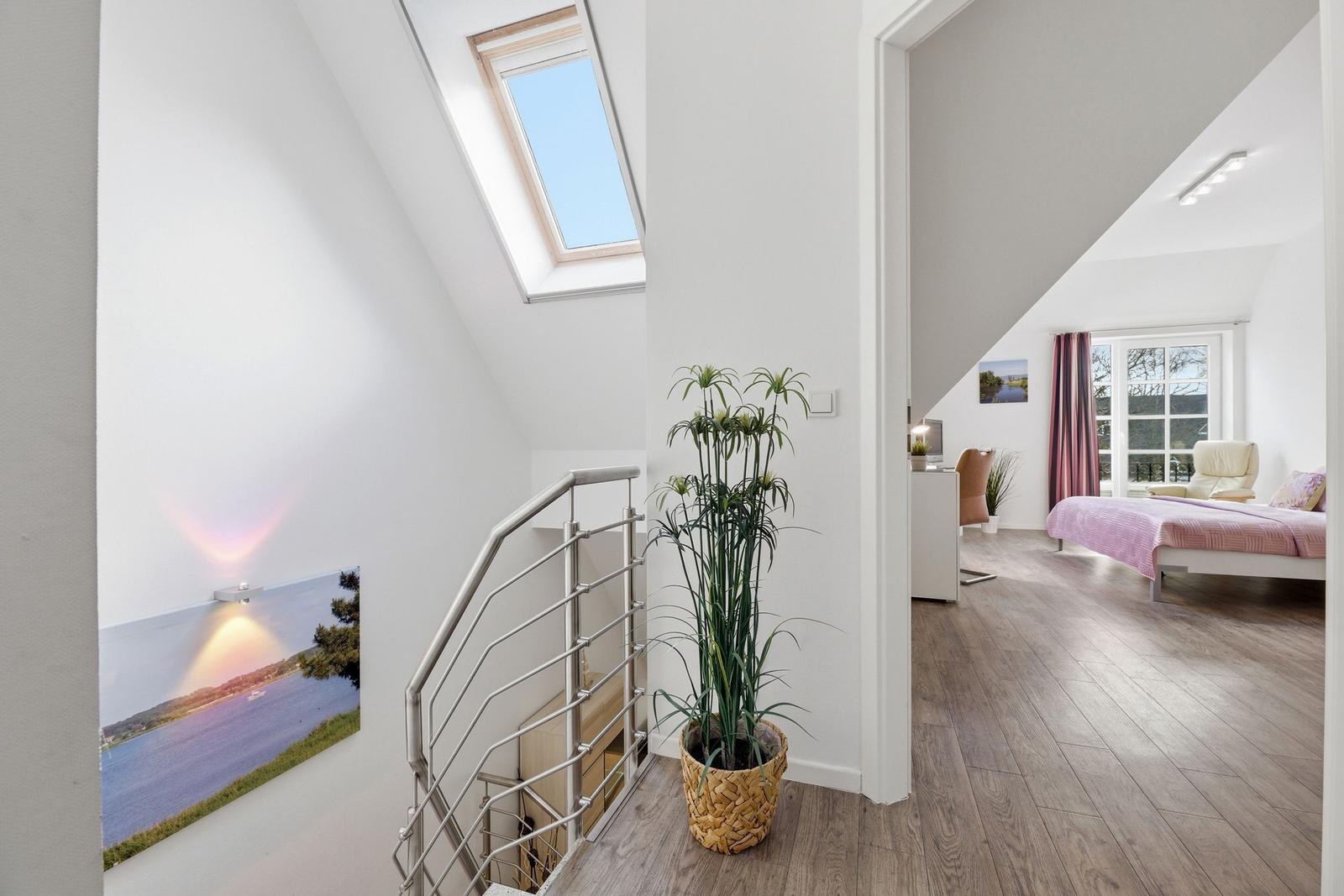 Staircase with skylight and room with bed and window