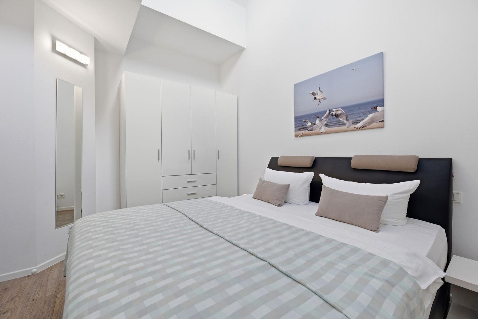 Bedroom with bed, wardrobe, and wall art of seagulls.
