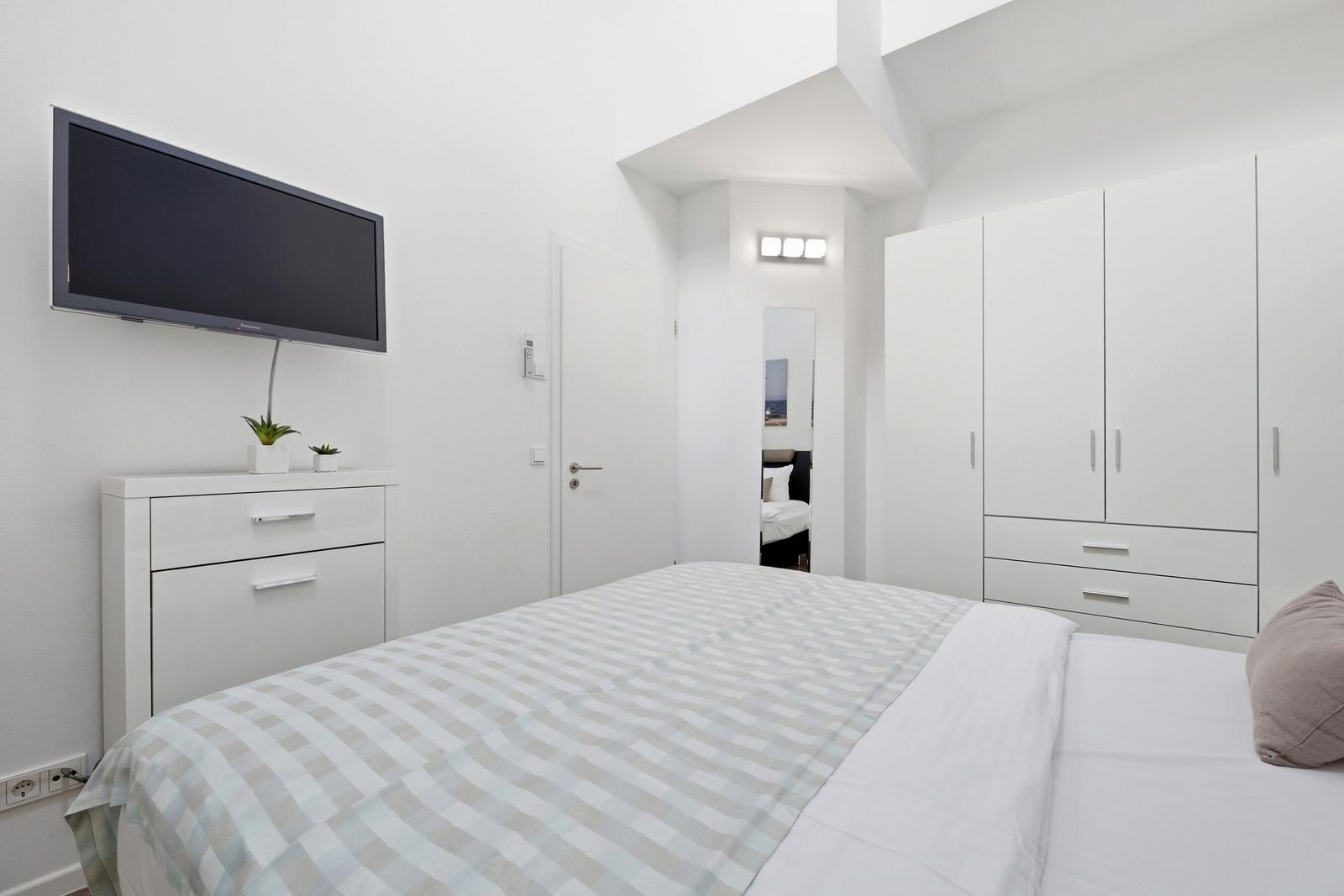 Bedroom with bed, wardrobe, and wall-mounted TV
