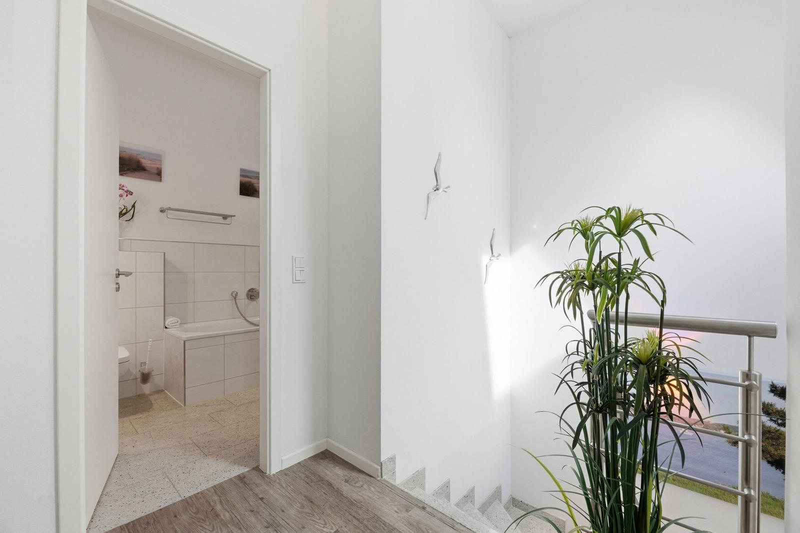 Hallway with bathroom and staircase, wall decor and houseplant