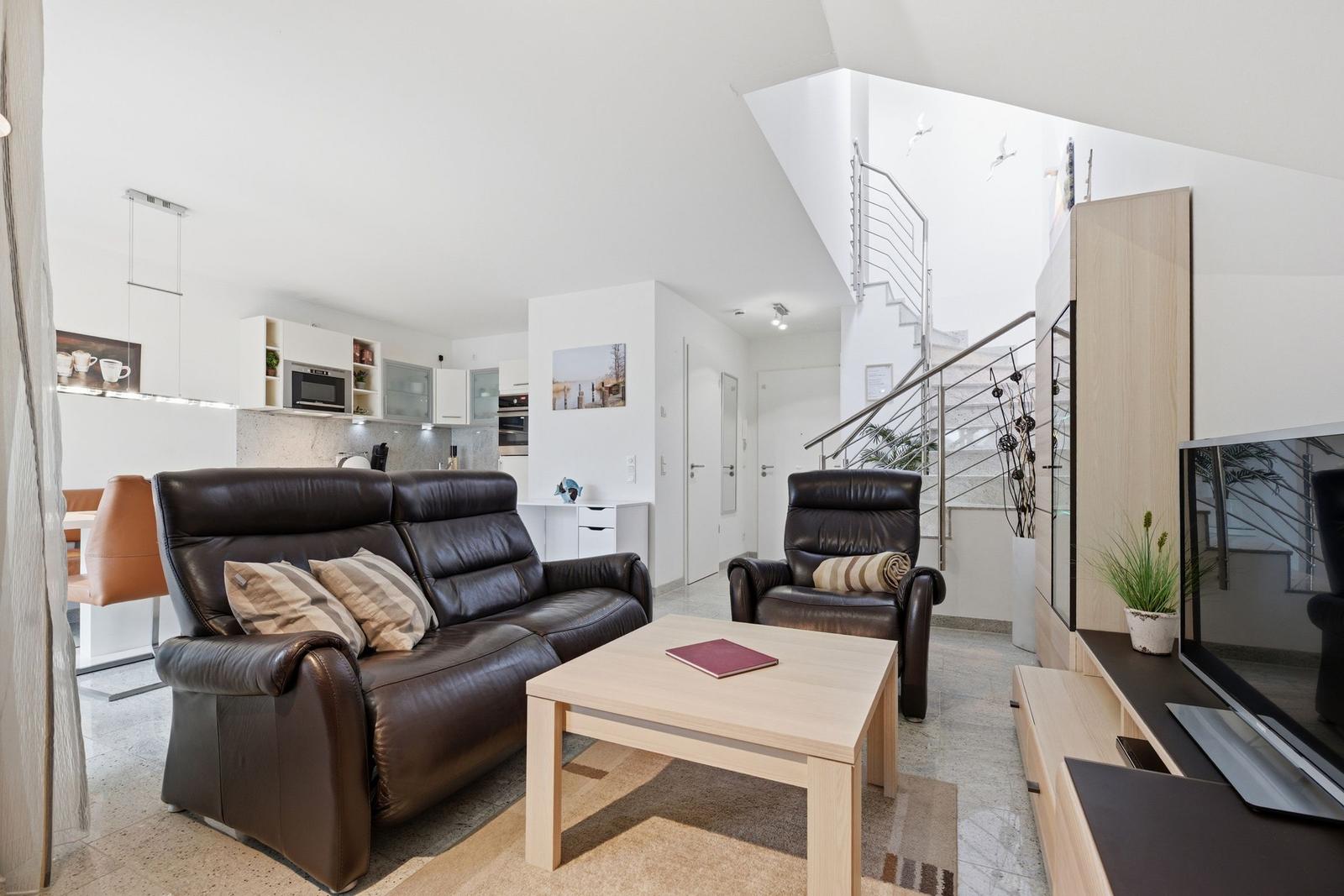 Living room with leather sofa, coffee table, and staircase.
