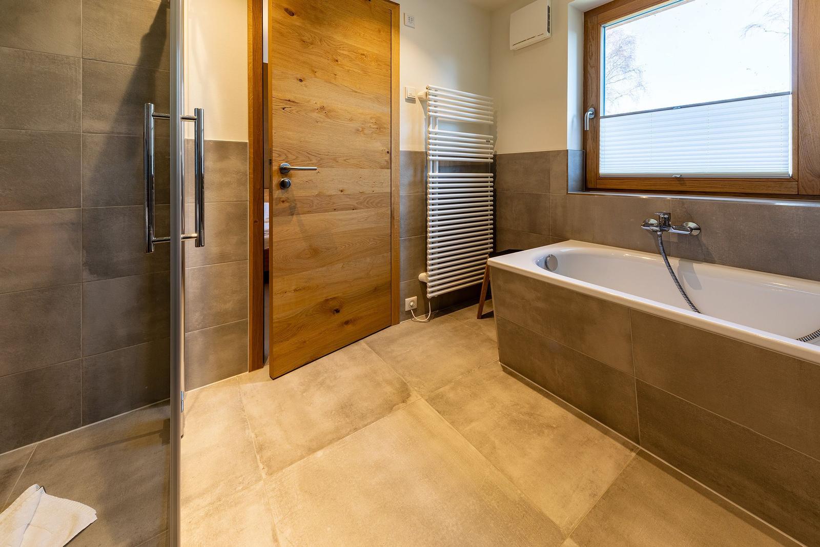 Badezimmer mit Badewanne, Dusche und Fenster