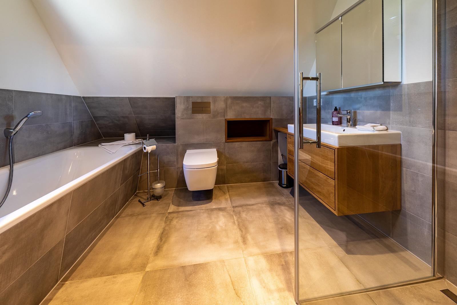 Badezimmer mit Badewanne, Toilette und Waschtisch mit Spiegelschrank.