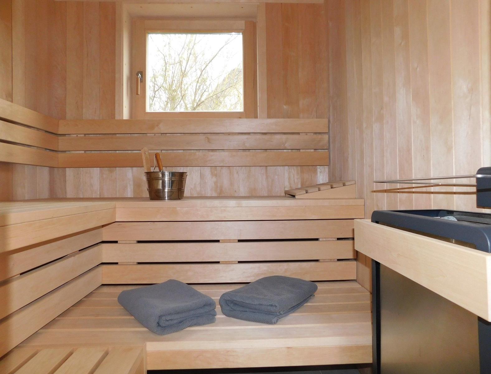 Sauna mit Holzbank, Fenster und zwei Handtüchern.