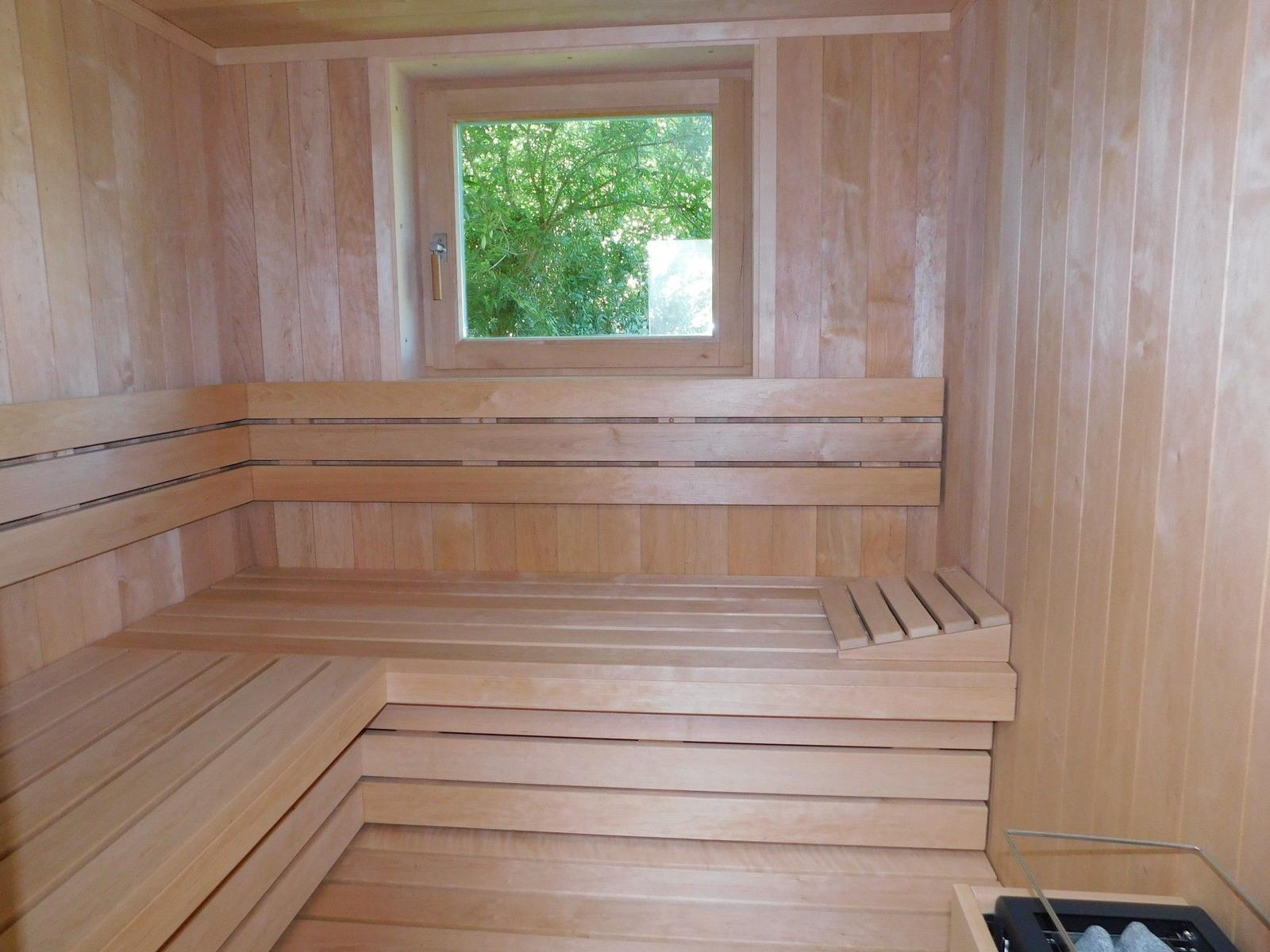 Sauna mit Holzbank und Fenster zur Außenseite.