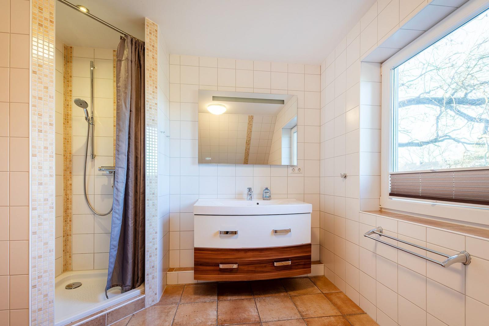Badezimmer mit Dusche, Waschbecken und Fenster