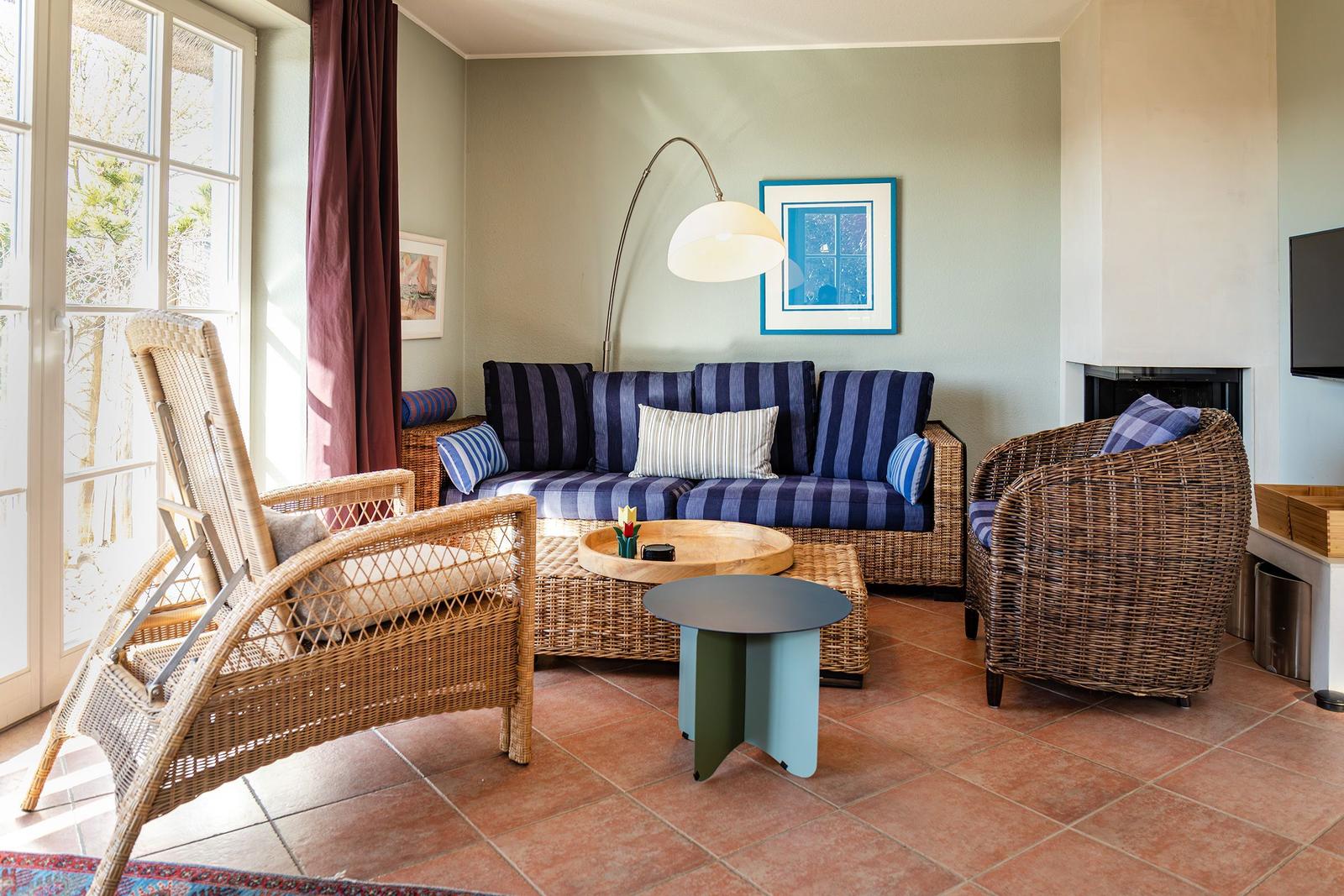 Wohnzimmer mit Rattanmöbeln, Sofa mit Streifenkissen und Kamin