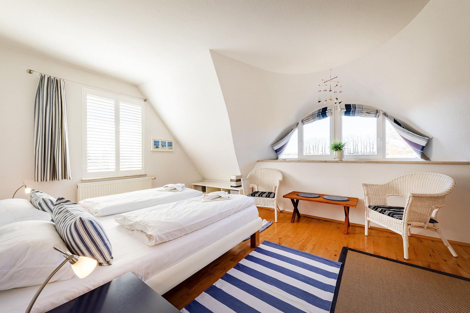 Zimmer mit Doppelbett, zwei Stühlen und Fenster mit Blick.