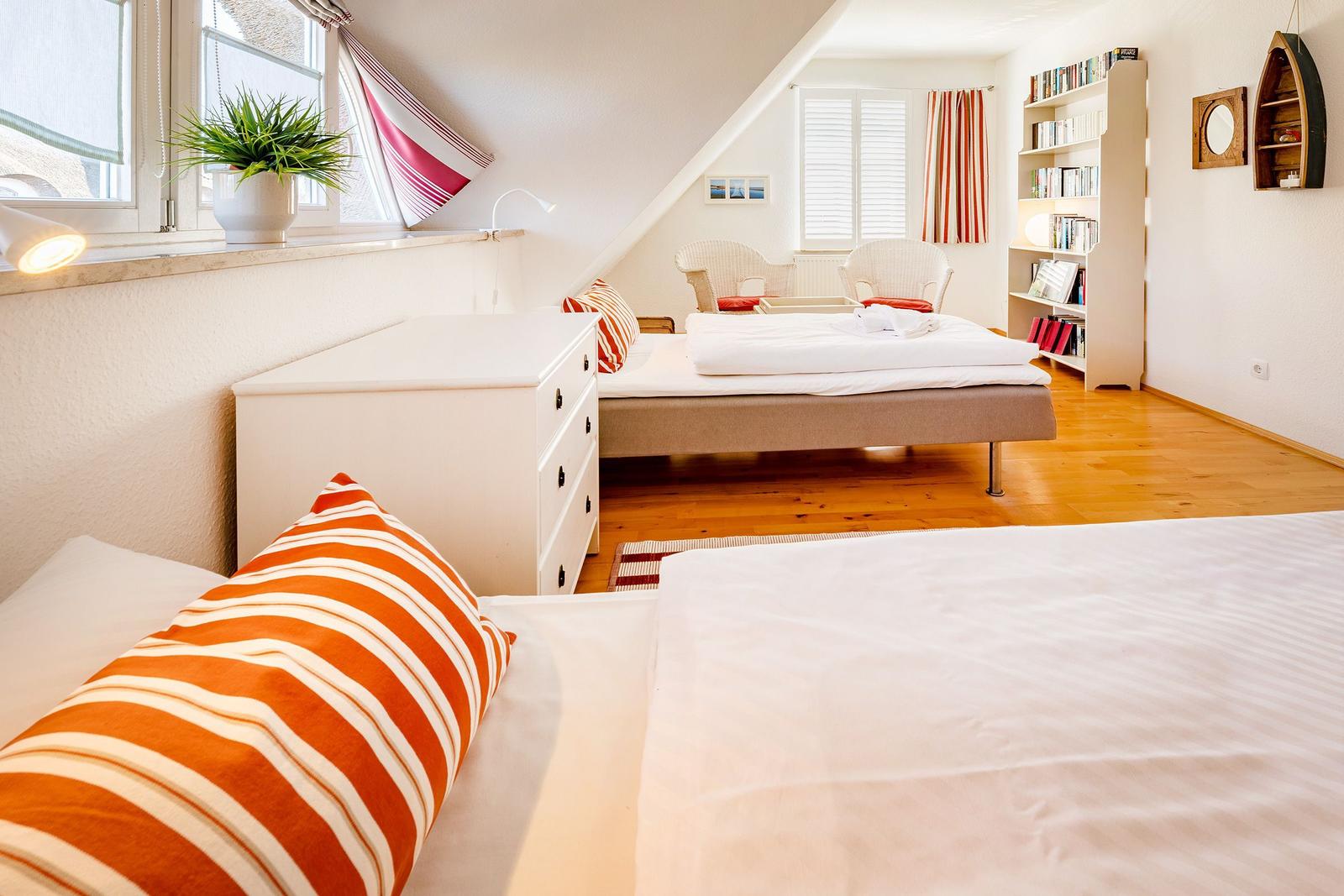 Zimmer mit zwei Betten, Schrank, Bücherregal und Fenster mit Blick.