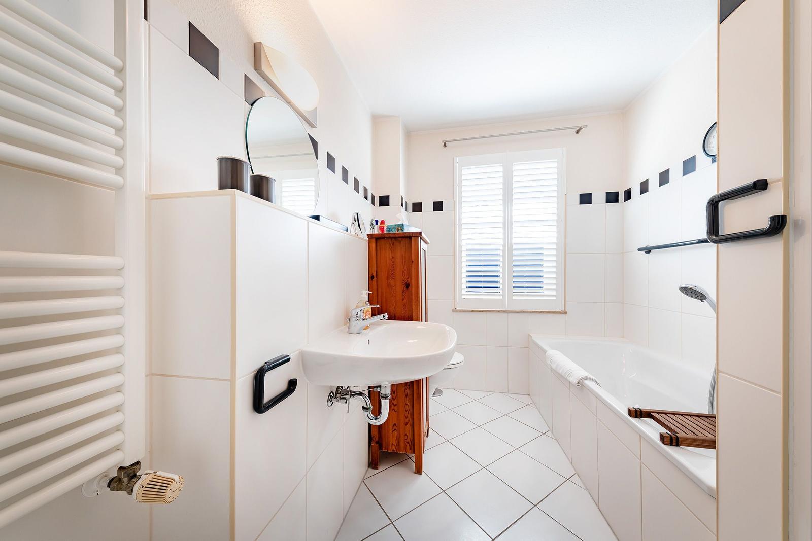 Badezimmer mit Badewanne, Waschbecken und Heizkörper