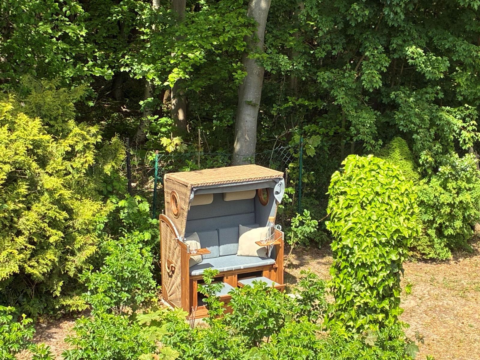 Wicker-Sonnenschutz mit Sitzfläche und Kissen im Grünen.