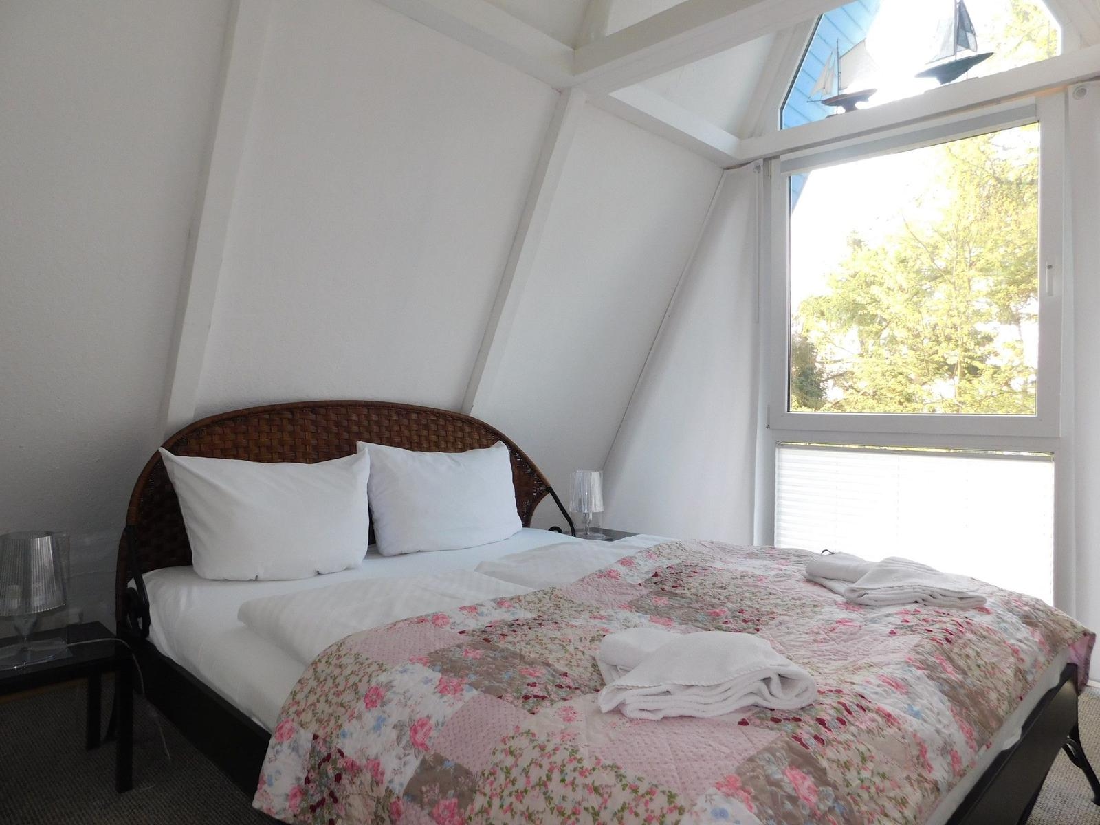Schlafzimmer mit Bett, Fenster und Deckenbalken