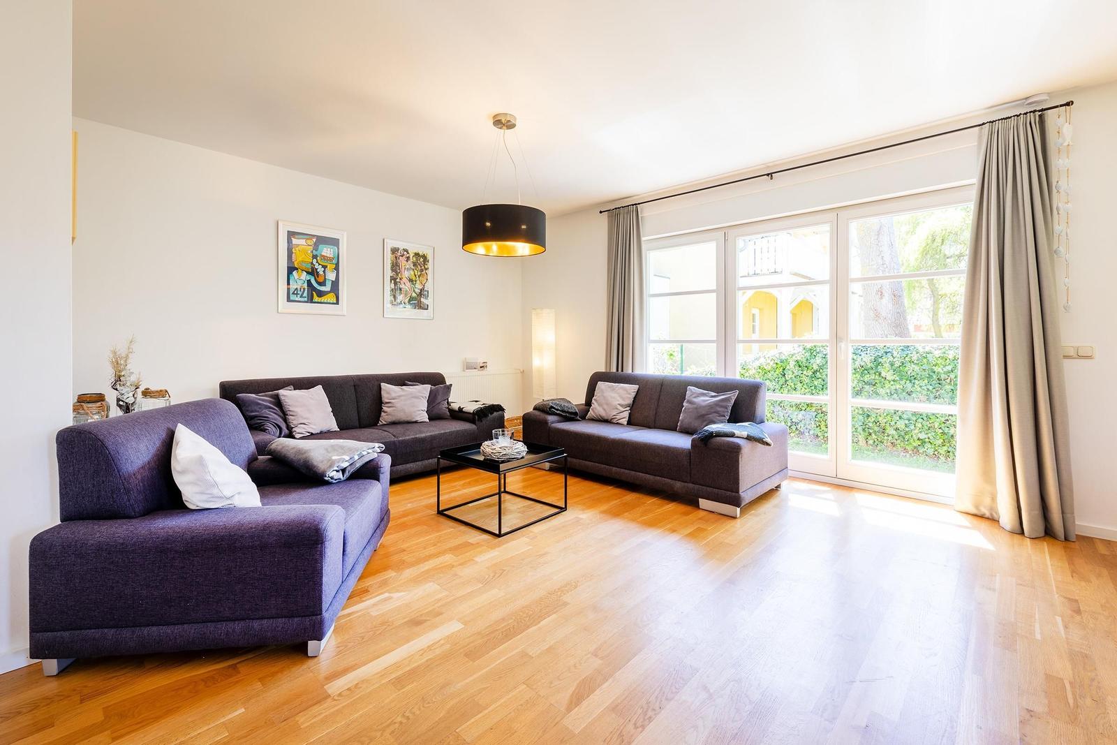 Wohnzimmer mit zwei Sofas, Holzboden und Fenster zur Außenterrasse.
