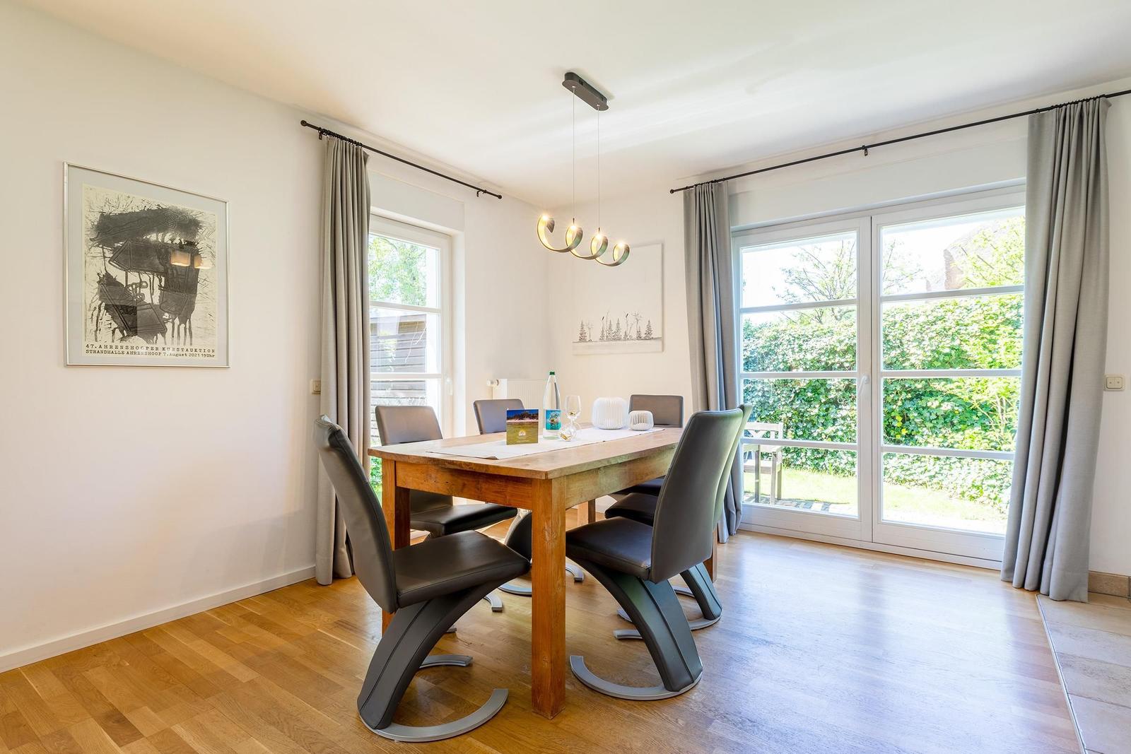 Esszimmer mit Holztisch, Stühlen und Blick auf den Garten.