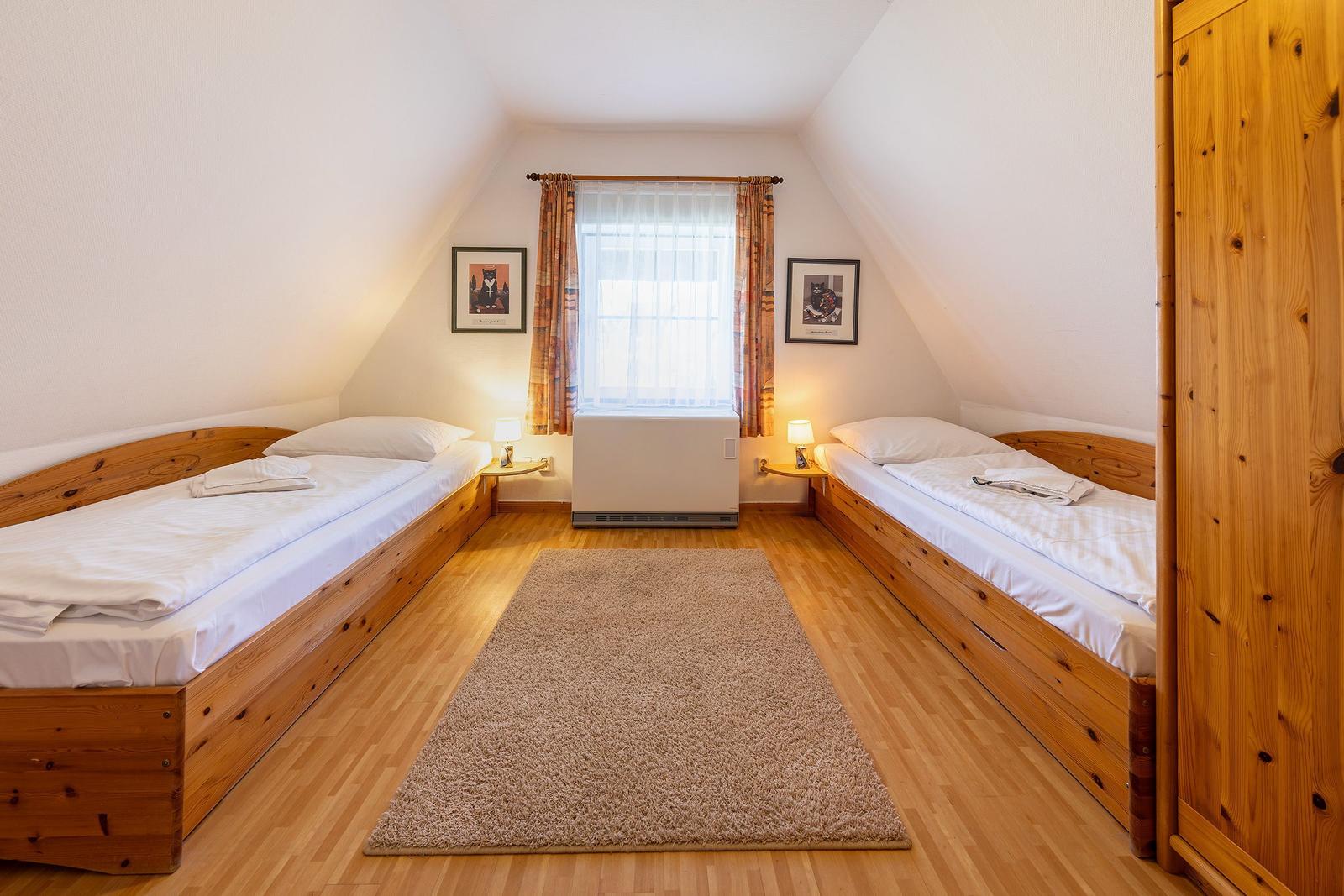 Zwei Einzelbetten, Holzboden, Fenster mit Vorhängen, Kleiderkammer