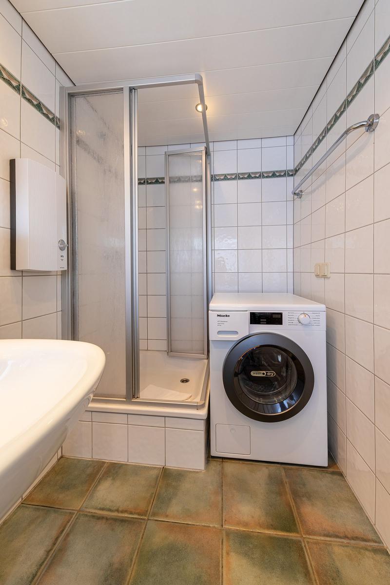 Badezimmer mit Dusche, Waschmaschine und Waschbecken