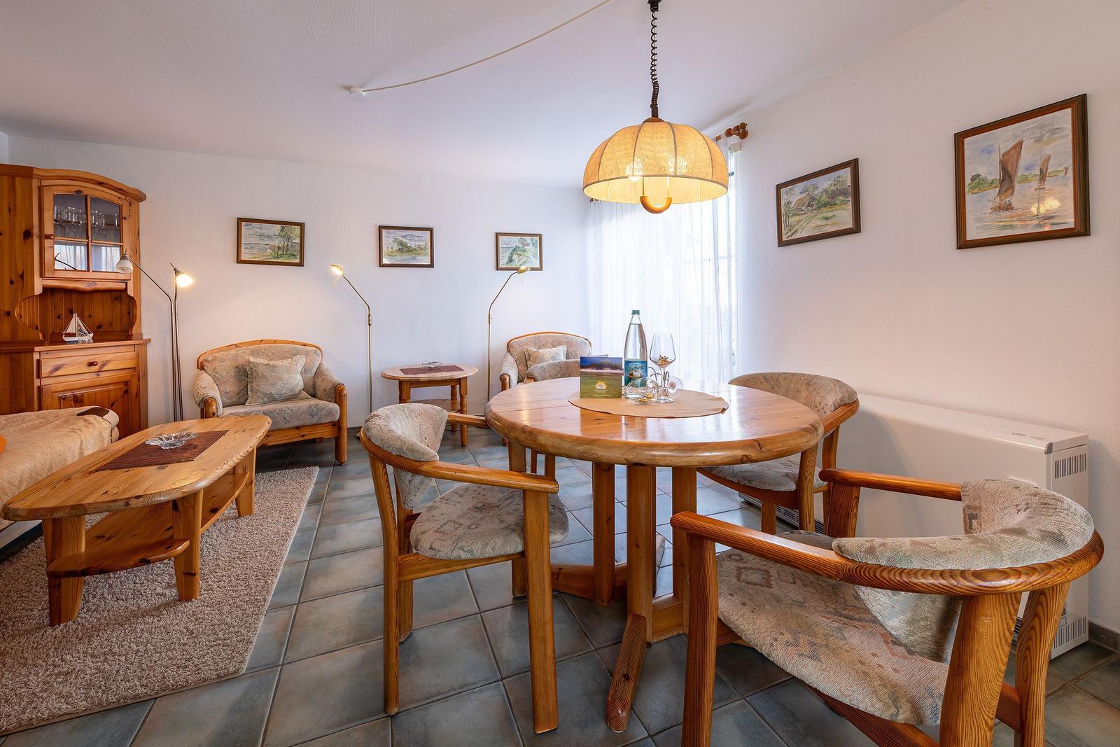 Esszimmer mit runden Tisch und Holzstühlen, Wandbildern und Lampen.