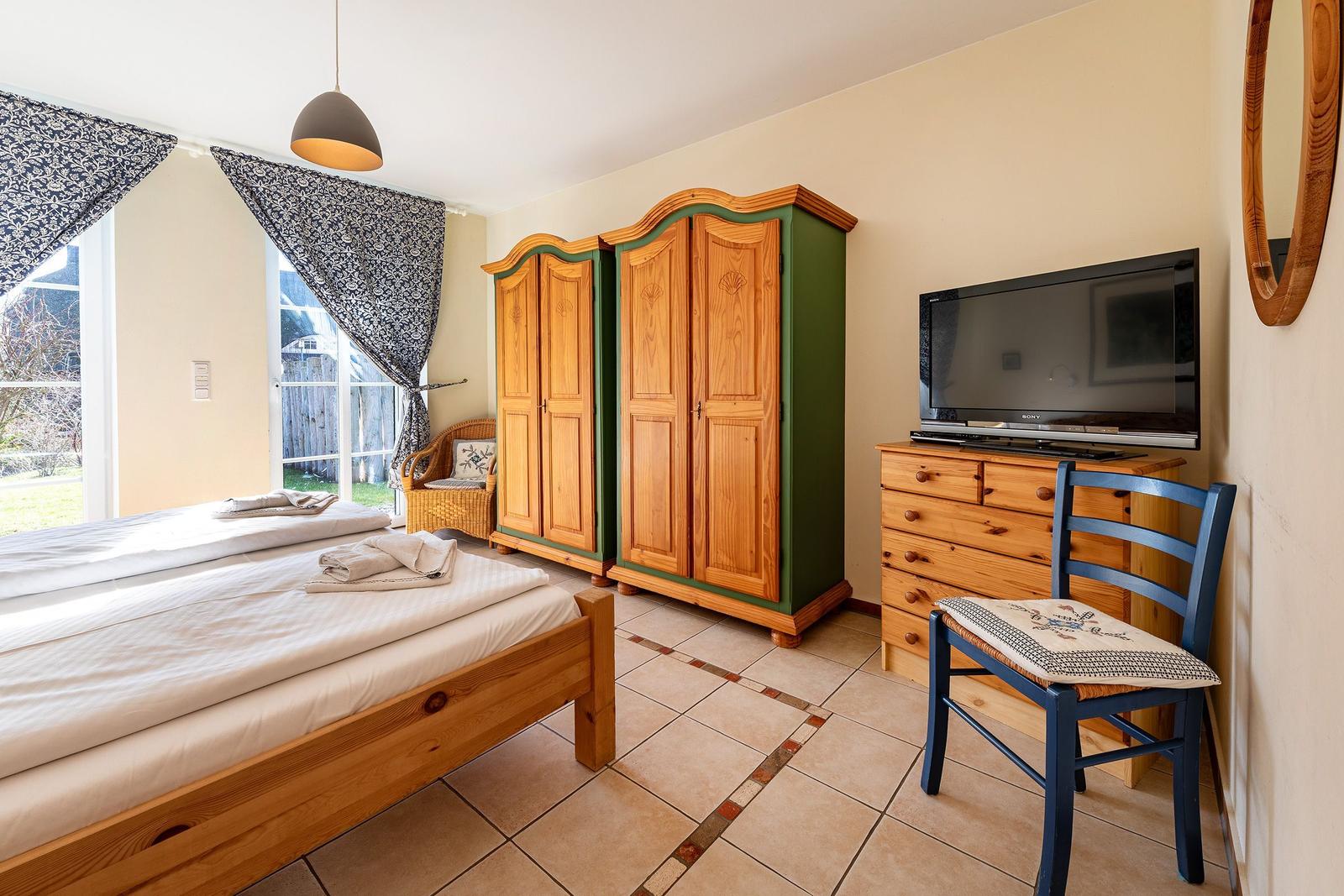 Schlafzimmer mit Bett, Kleiderschränken, Fernseher und Stuhl.