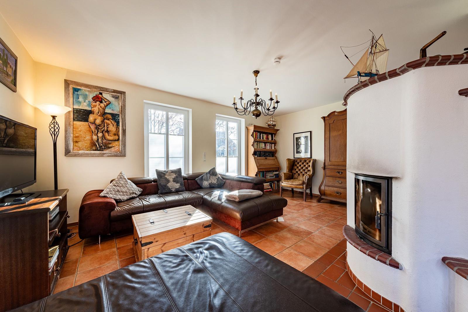 Wohnzimmer mit Ledersofa, Kamin und Holzmöbeln. Wandbild und Stehlampe sichtbar.