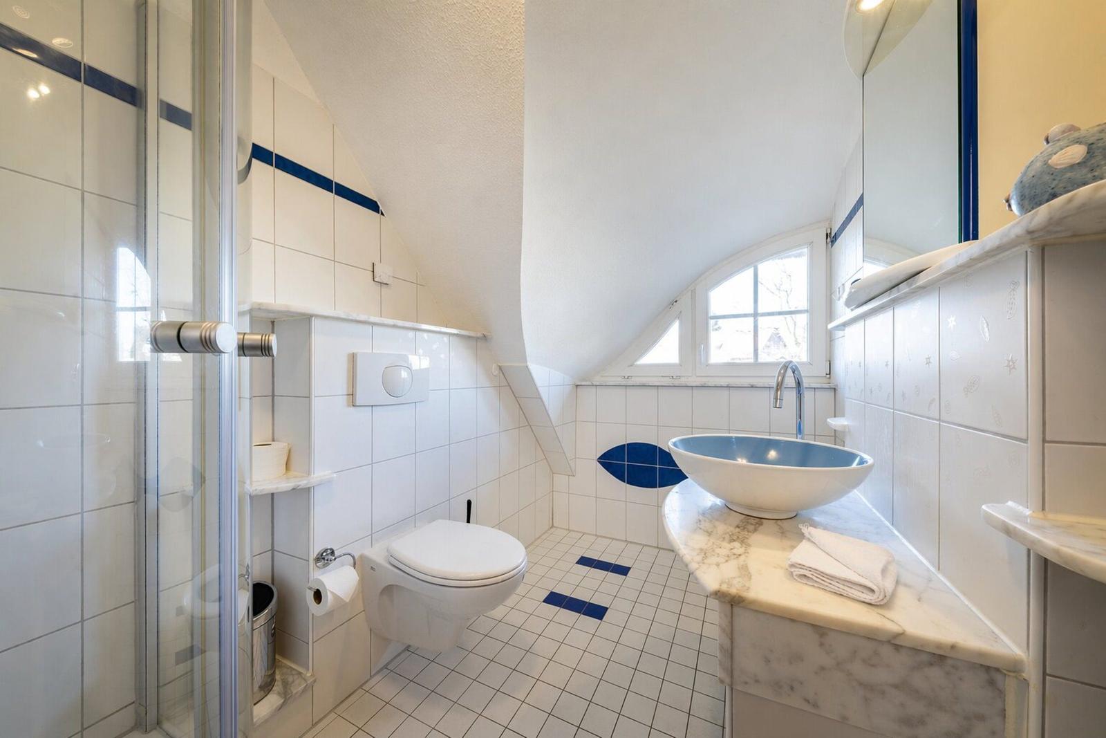 Badezimmer mit Dusche, Toilette und Waschbecken auf Marmorplatte.