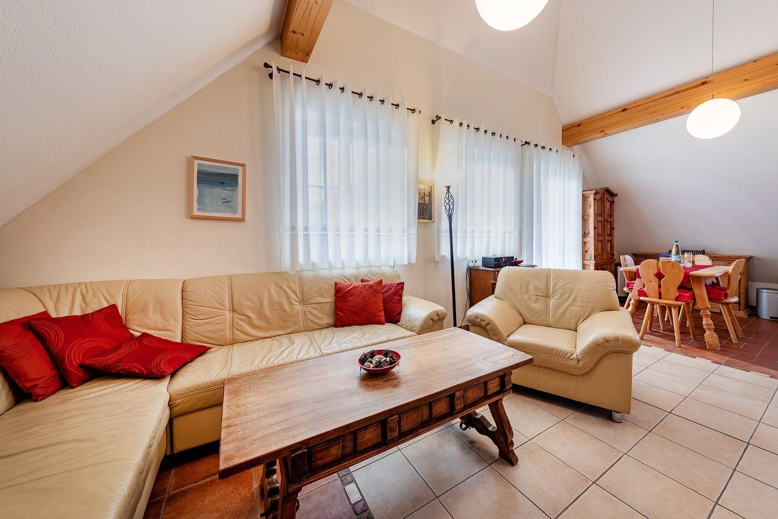 Wohnzimmer mit Ledersofa, Holztisch und Essbereich mit Holzstühlen.