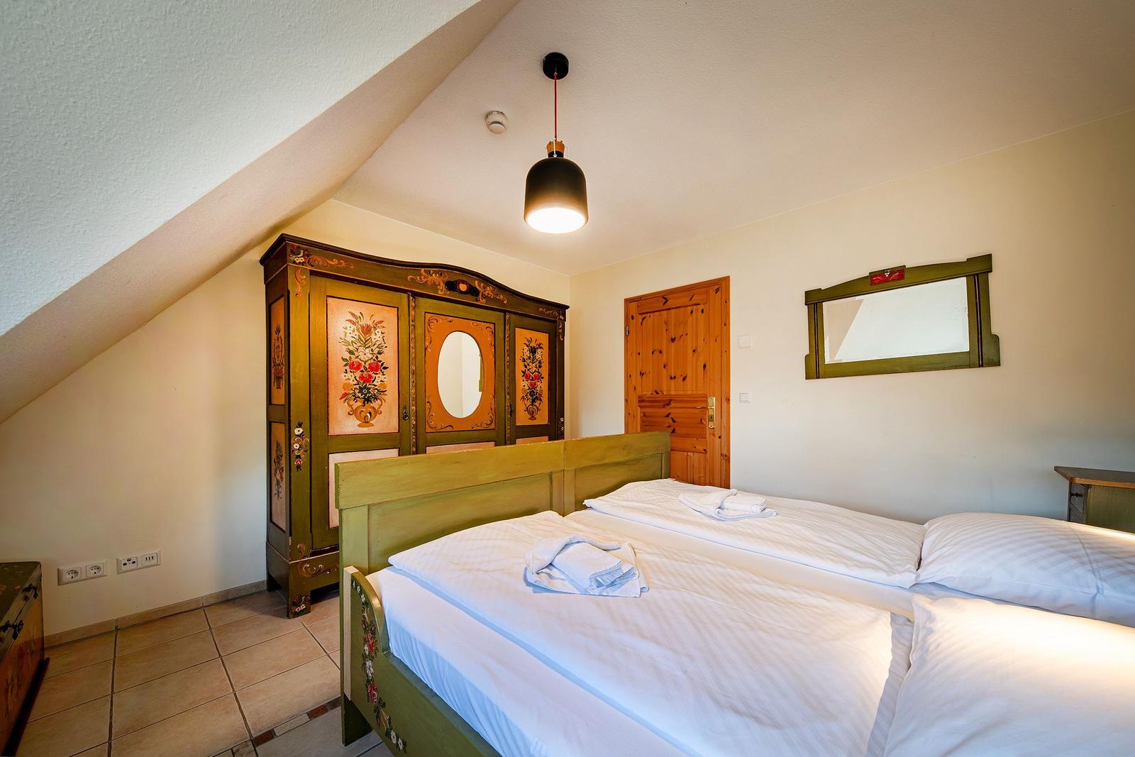Schlafzimmer mit Doppelbett, dekorativem Schrank und Spiegel an der Wand.