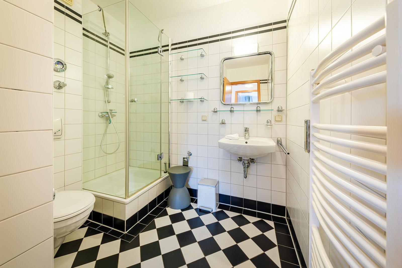 Badezimmer mit Dusche, Waschbecken und Heizkörper