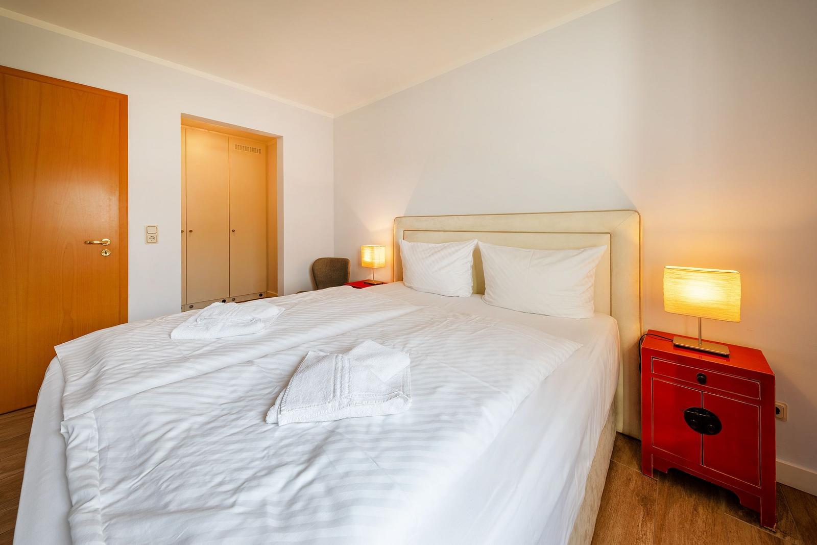 Ein Schlafzimmer mit Doppelbett, zwei Nachttischen und einer Tür.
