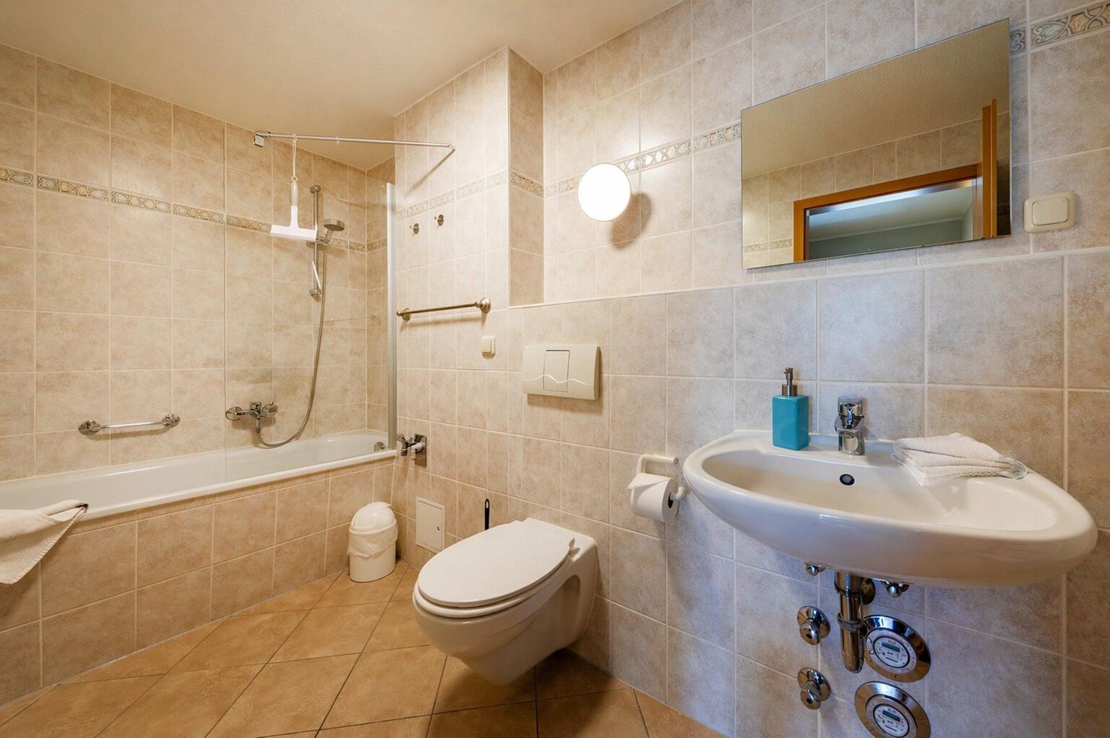 Badezimmer mit Badewanne, Dusche, Toilette und Waschbecken.